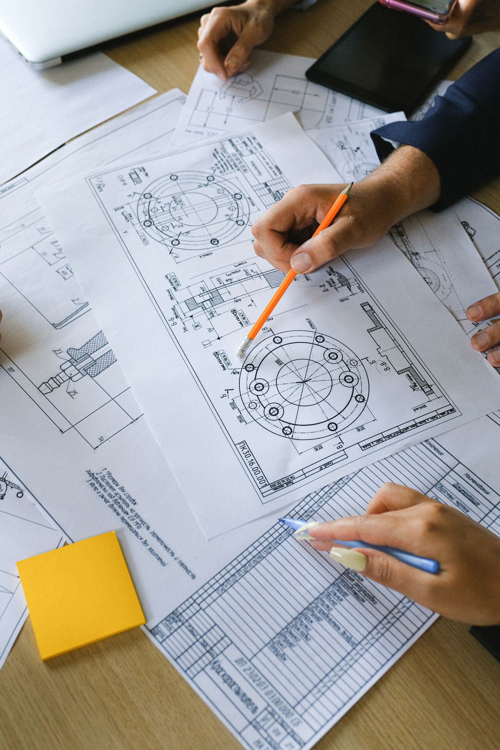 Hands reviewing mechanical engineering drawings